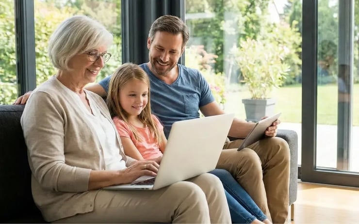 Familie nutzt Laptop und Tablet im Wohnzimmer