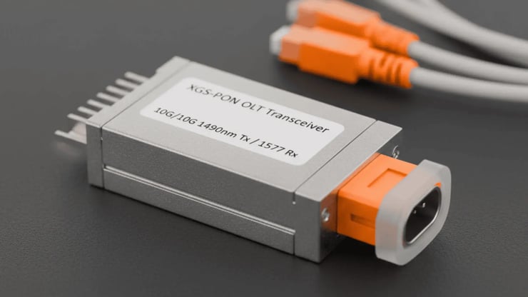 Nahaufnahme eines XGS-PON OLT-Transceivers mit angeschlossenen orangefarbenen Glasfaserkabeln – zentrale Hardwarekomponente im Glasfaser-Netz von DNS:NET.